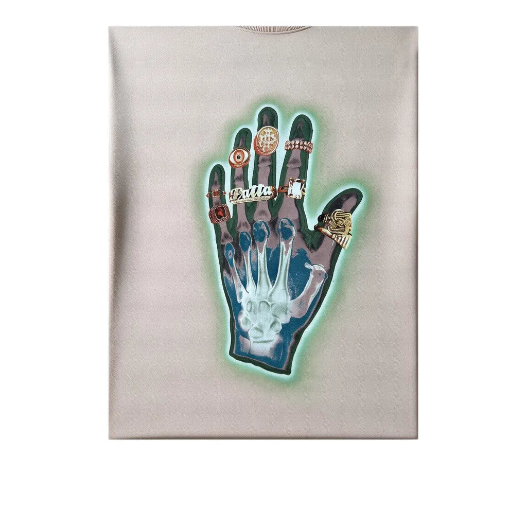 Urban Cult T-shirt Patta 'Healing Hands' rosa pastello in cotone pesante con grafica di una mano scheletrica con anelli dorati e aura verde neon.